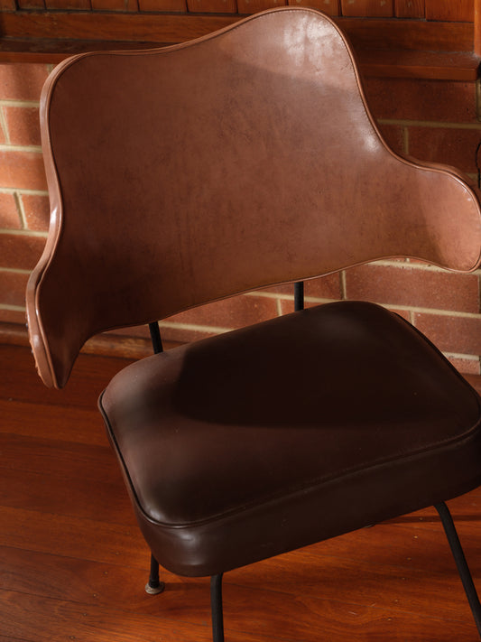 Mid-Century brown leather dining chair with padded seat and sculpted backrest on slim metal legs