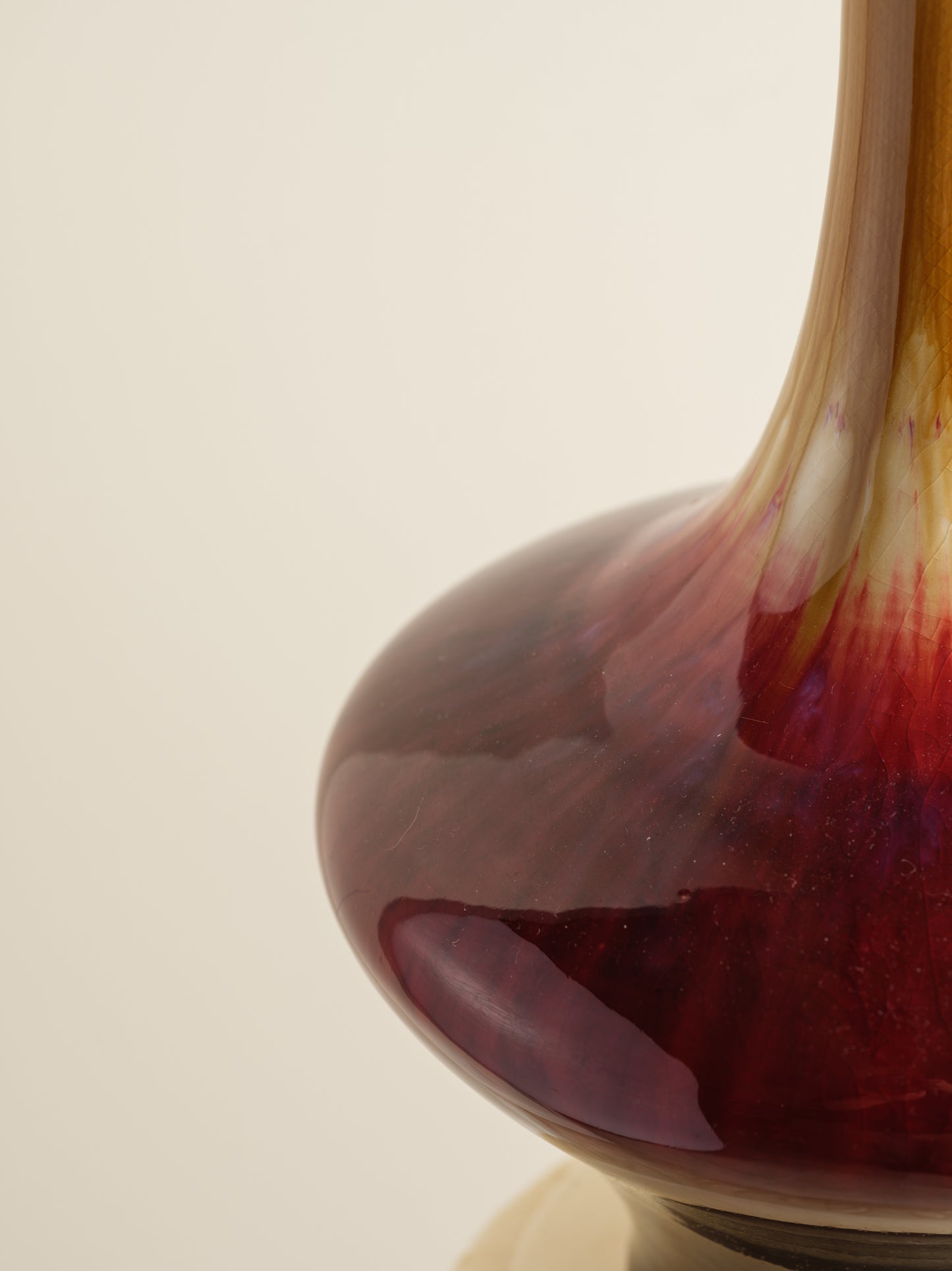 Flambé-glazed vase with a flared neck and rich gradient of crimson, amber, and deep oxblood hues.