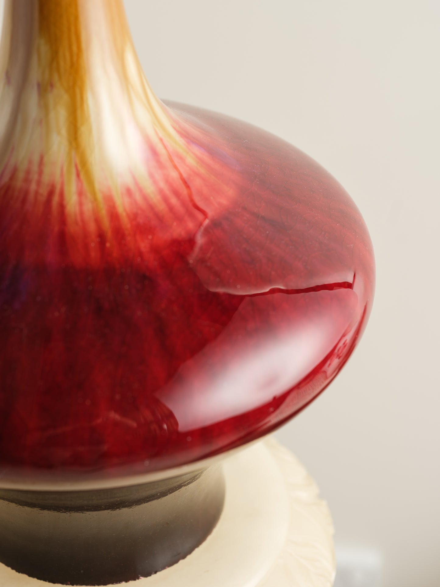 Flambé-glazed vase with a flared neck and rich gradient of crimson, amber, and deep oxblood hues.