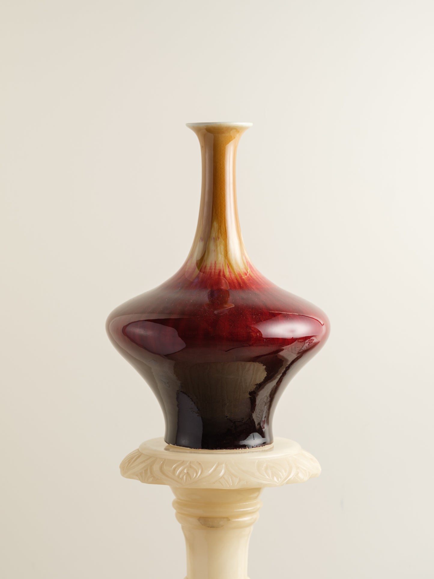 Flambé-glazed vase with a flared neck and rich gradient of crimson, amber, and deep oxblood hues.