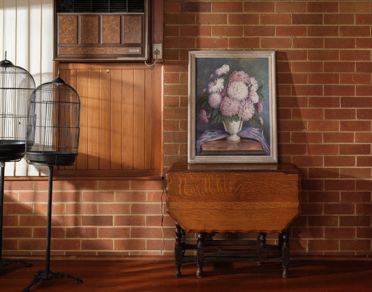 Oil painting titled Blush Chrysanthemums in White Vase, featuring a lush bouquet of pink chrysanthemums arranged in a classic white vase with a striped blue cloth.