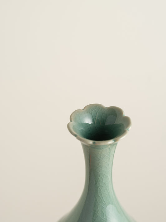 Song Whisper Celadon Vase, a delicate ceramic vessel with a slender flared neck and subtle engraved figure motif on a pale green glaze.