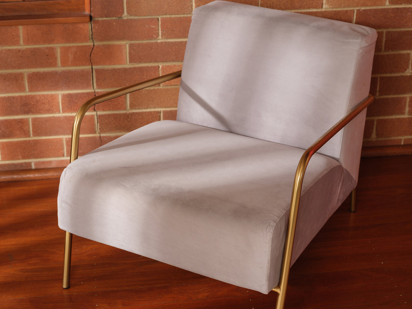 Contemporary lounge accent chair with soft grey upholstery and gold metal frame