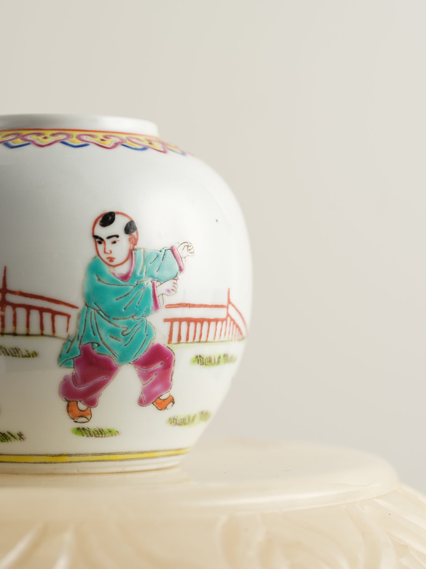 Small porcelain jar hand-painted with playful courtyard children in bright traditional robes.