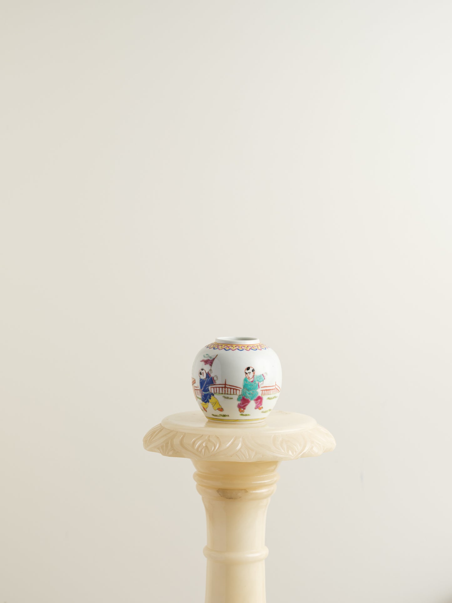 Small porcelain jar hand-painted with playful courtyard children in bright traditional robes.