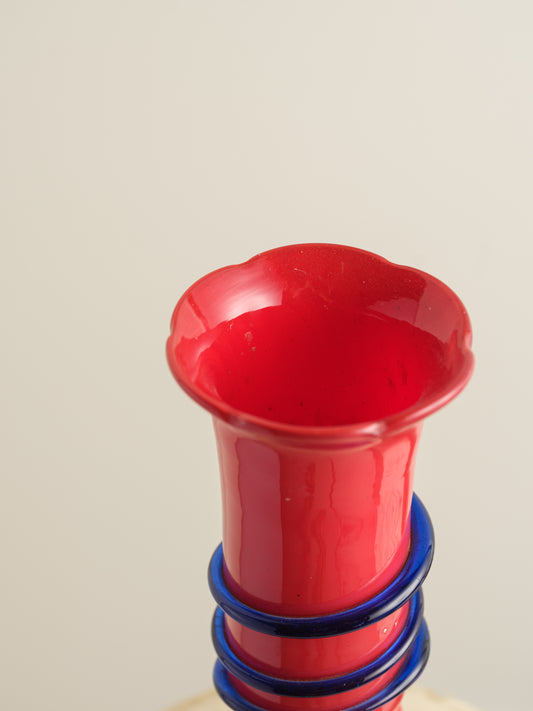 Red glass bud vase with flared rim and cobalt spiral accent wrapping around the neck.