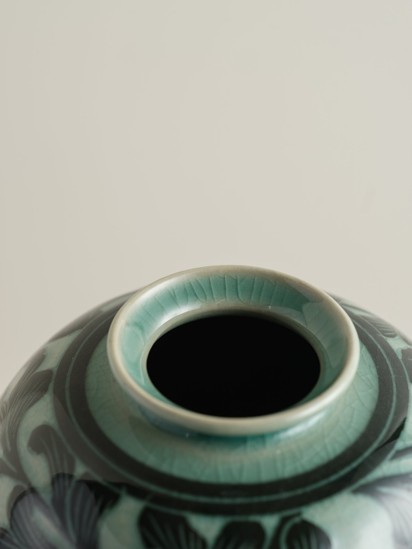 Hand-painted ceramic jar in deep green tones with scrolling leaf and floral patterns.