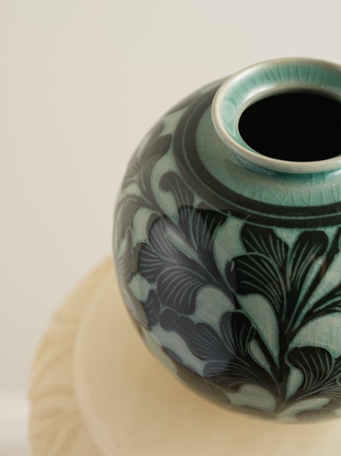 Hand-painted ceramic jar in deep green tones with scrolling leaf and floral patterns.