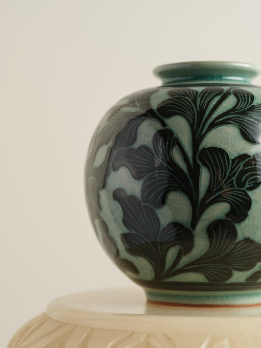 Hand-painted ceramic jar in deep green tones with scrolling leaf and floral patterns.