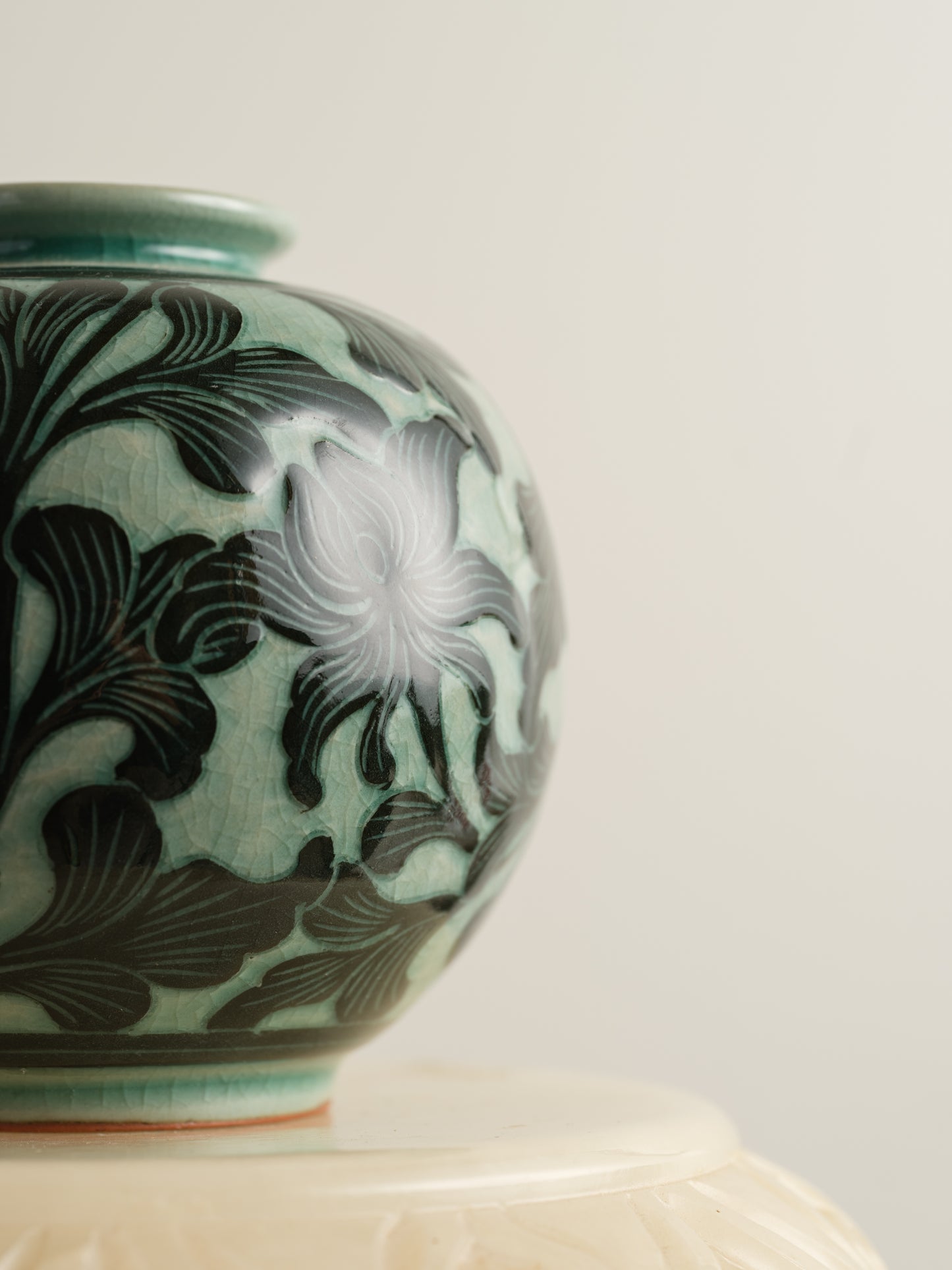 Hand-painted ceramic jar in deep green tones with scrolling leaf and floral patterns.