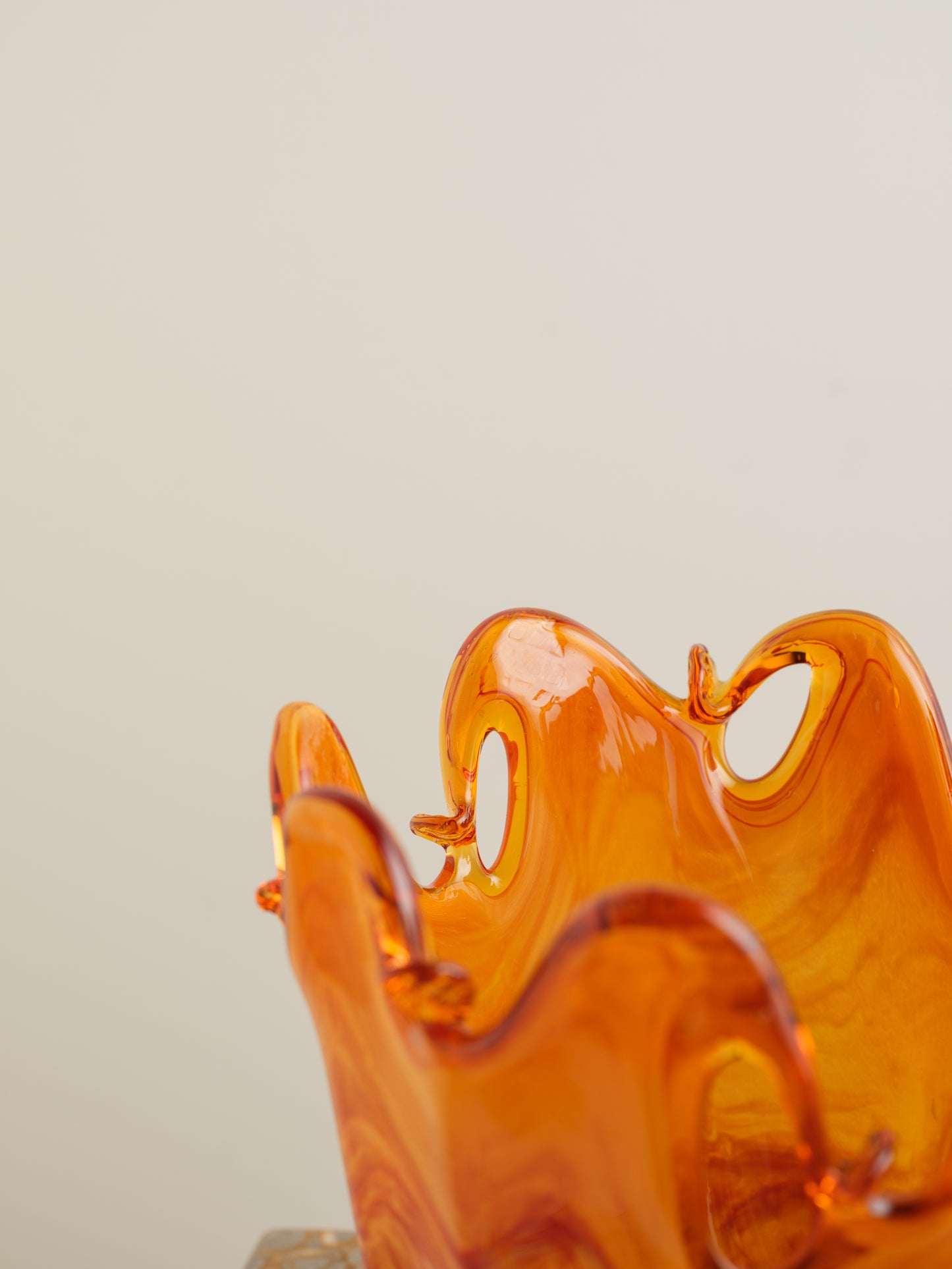 Handblown orange glass bowl with fluid wavy rim and marbled amber tones.