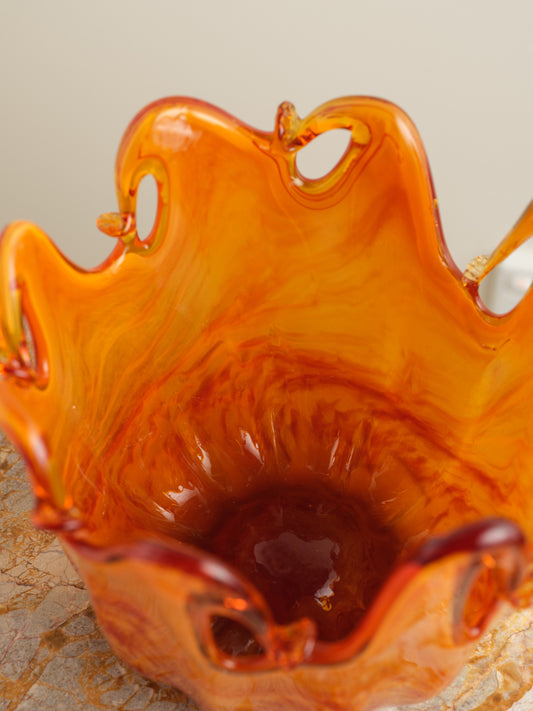Handblown orange glass bowl with fluid wavy rim and marbled amber tones.