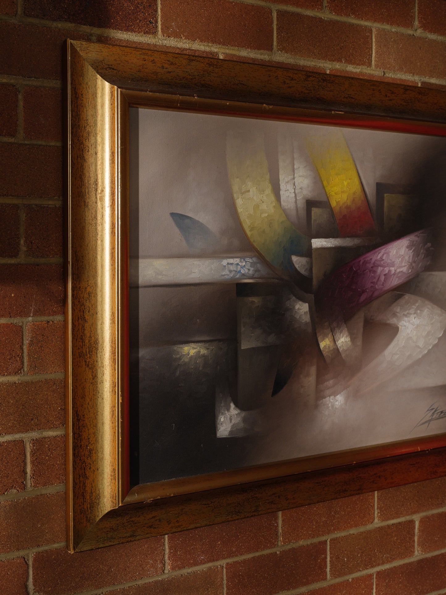 Oil painting titled Gilded Ribbons, featuring sweeping abstract curves in gold, crimson, and muted tones, layered over a smoky brown and grey background, framed in gold.