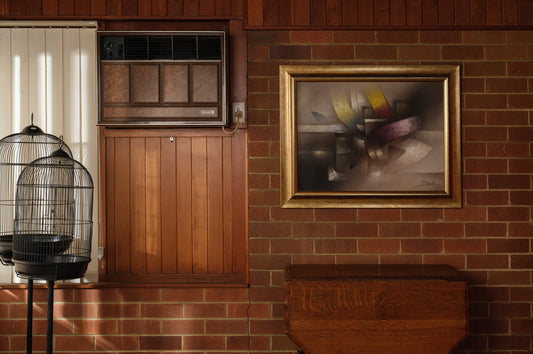 Oil painting titled Gilded Ribbons, featuring sweeping abstract curves in gold, crimson, and muted tones, layered over a smoky brown and grey background, framed in gold.