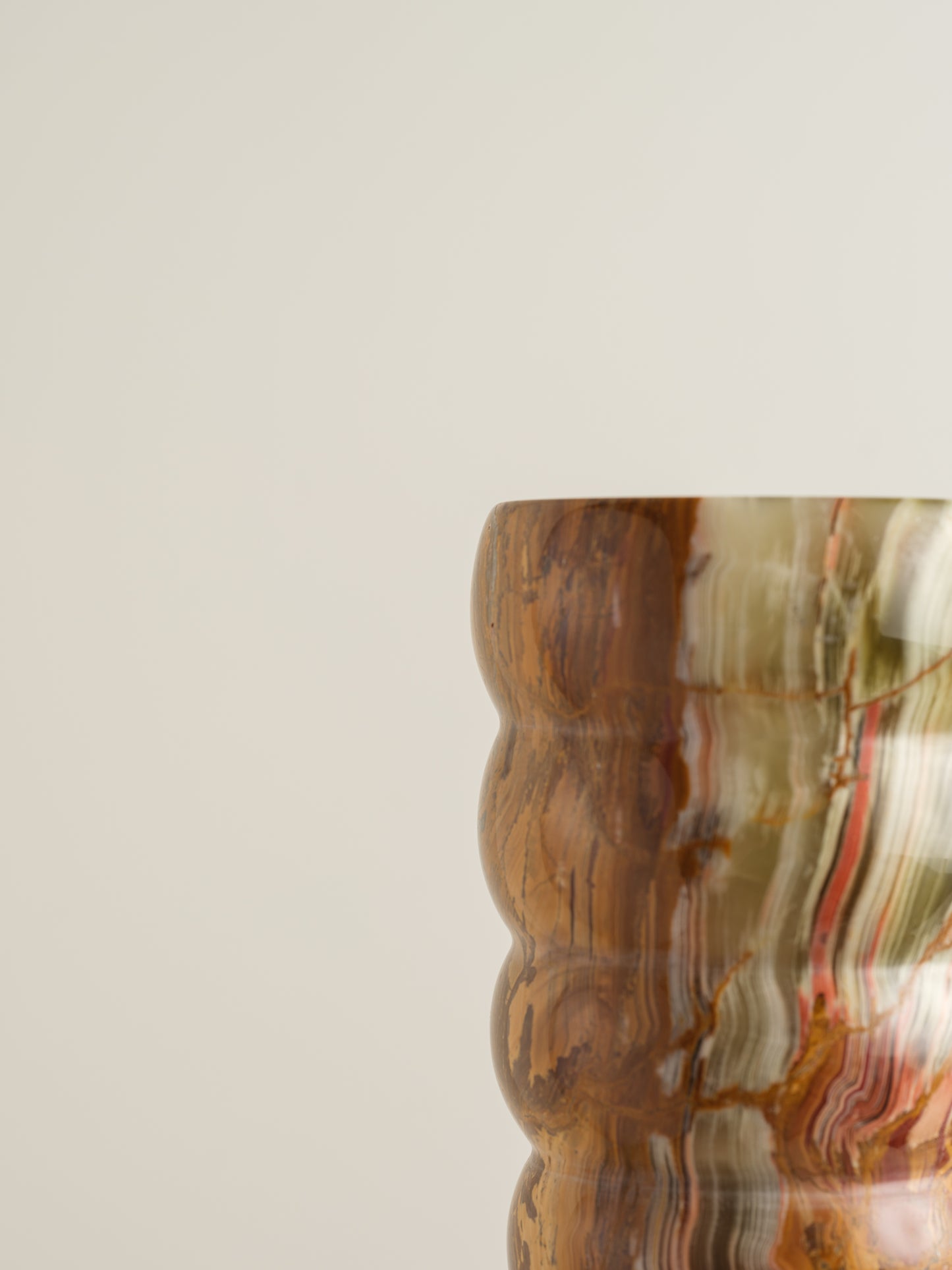 Honey Onyx Ripple Vase with natural striations in warm amber, cream, and green tones, carved in a rippled cylindrical form.