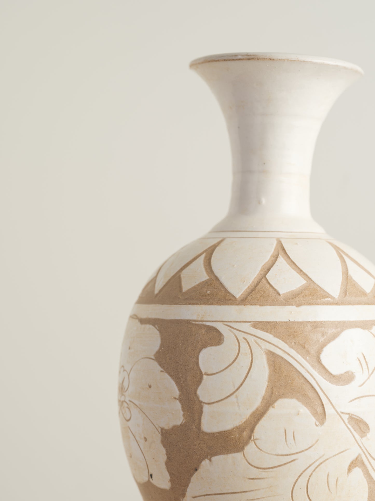 Ivory Blossom Sgraffito Vase, featuring hand-carved floral motifs in contrasting ivory and earthy tones with a traditional rounded body and flared neck.