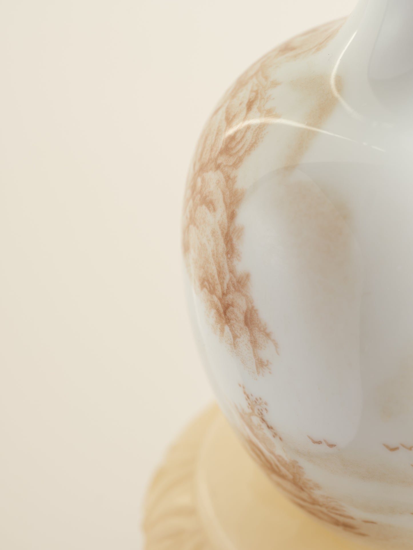 Porcelain vase with tea-wash glaze and hand-painted sepia landscape scene of mountains and flying birds.