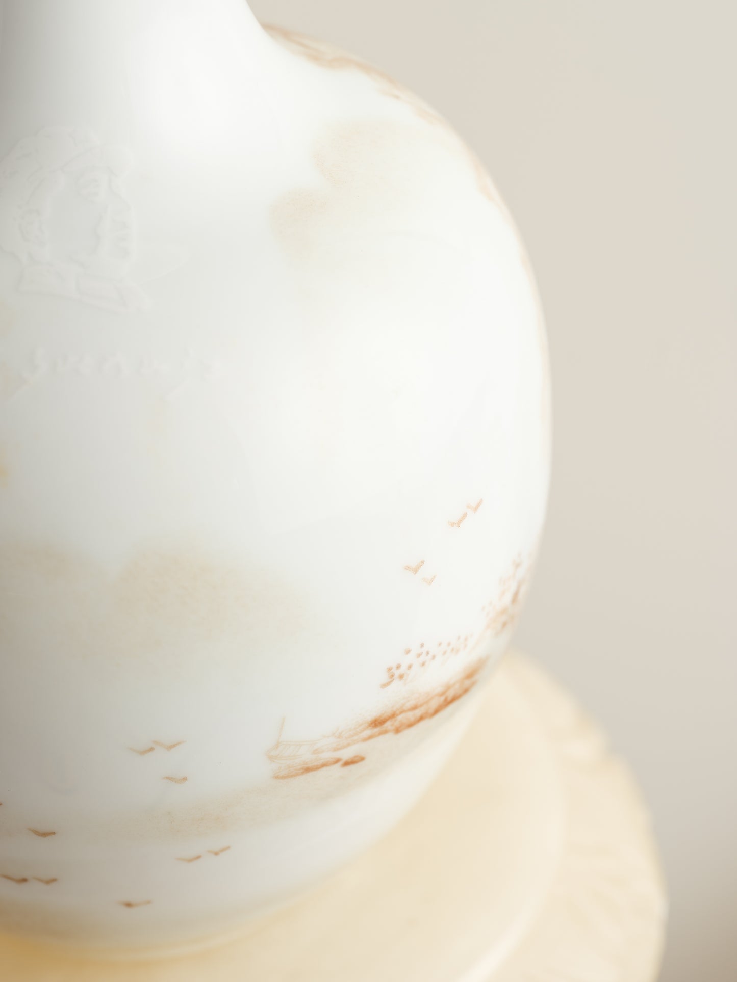 Porcelain vase with tea-wash glaze and hand-painted sepia landscape scene of mountains and flying birds.