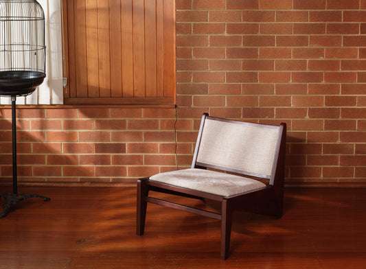 Low armchair with dark brown wooden frame and beige fabric upholstery, modern vintage design