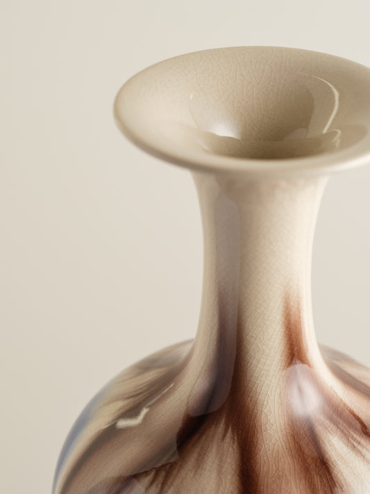 Porcelain vase with flowing drip-glaze in indigo, cream, and russet tones.