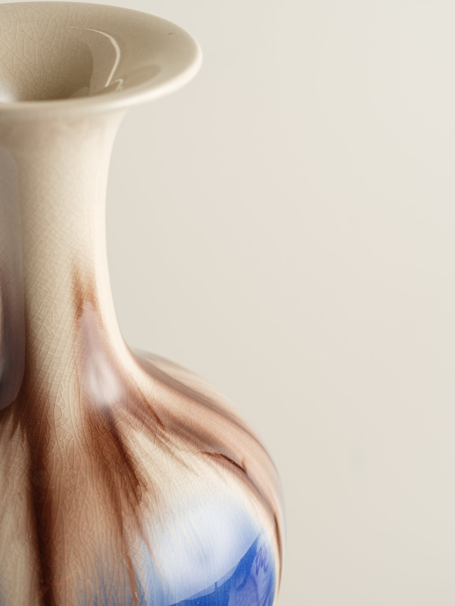 Porcelain vase with flowing drip-glaze in indigo, cream, and russet tones.