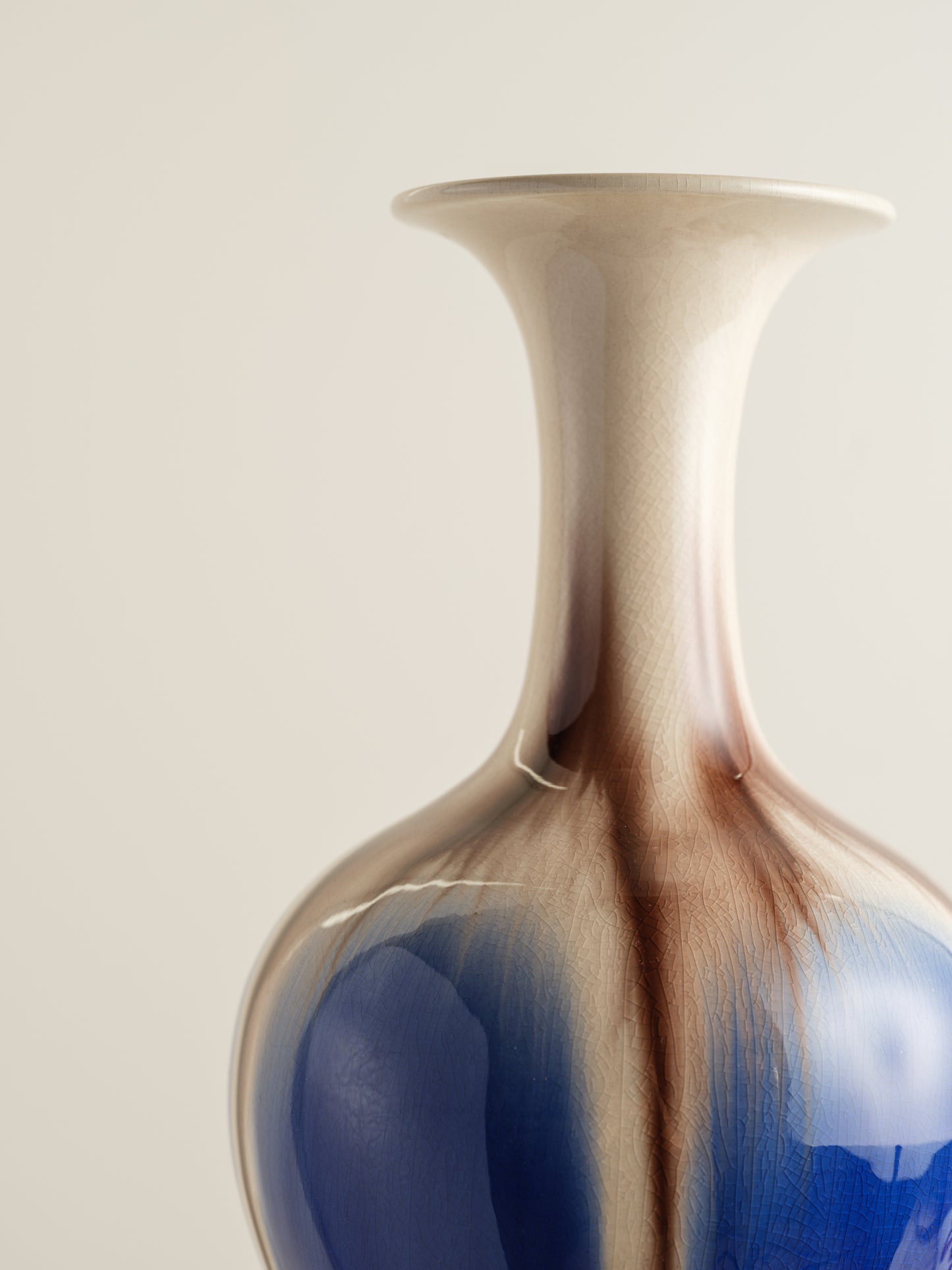 Porcelain vase with flowing drip-glaze in indigo, cream, and russet tones.