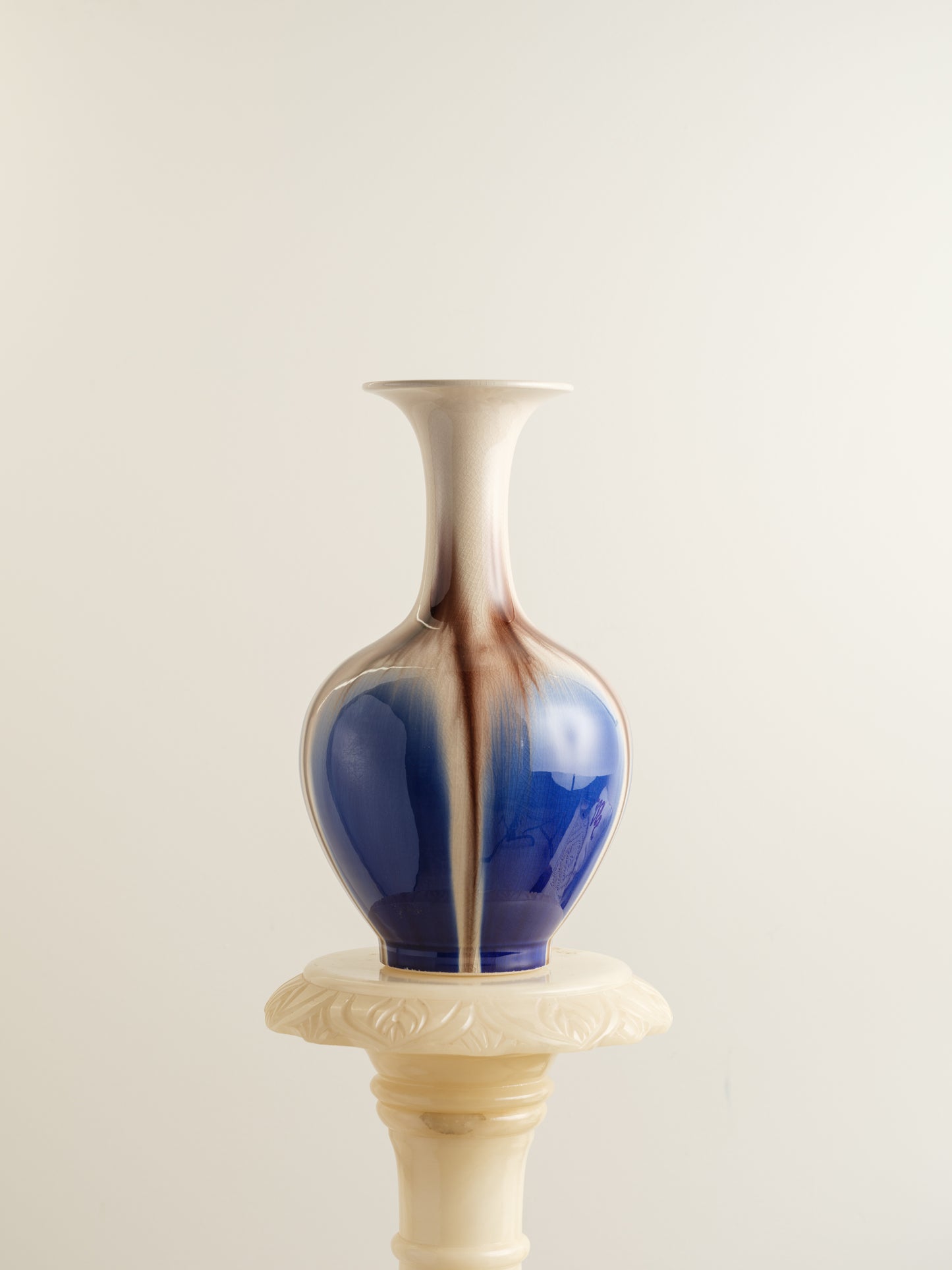 Porcelain vase with flowing drip-glaze in indigo, cream, and russet tones.