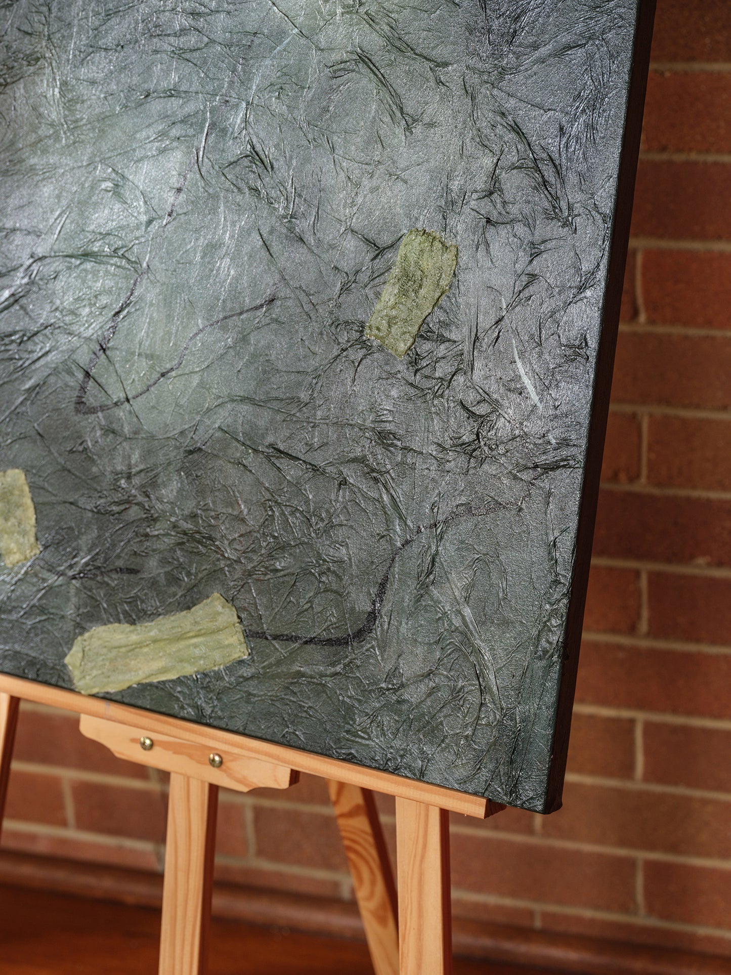 Abstract painting titled Moss & Slate Drift, featuring textured dark green and grey tones with organic golden accents on canvas.