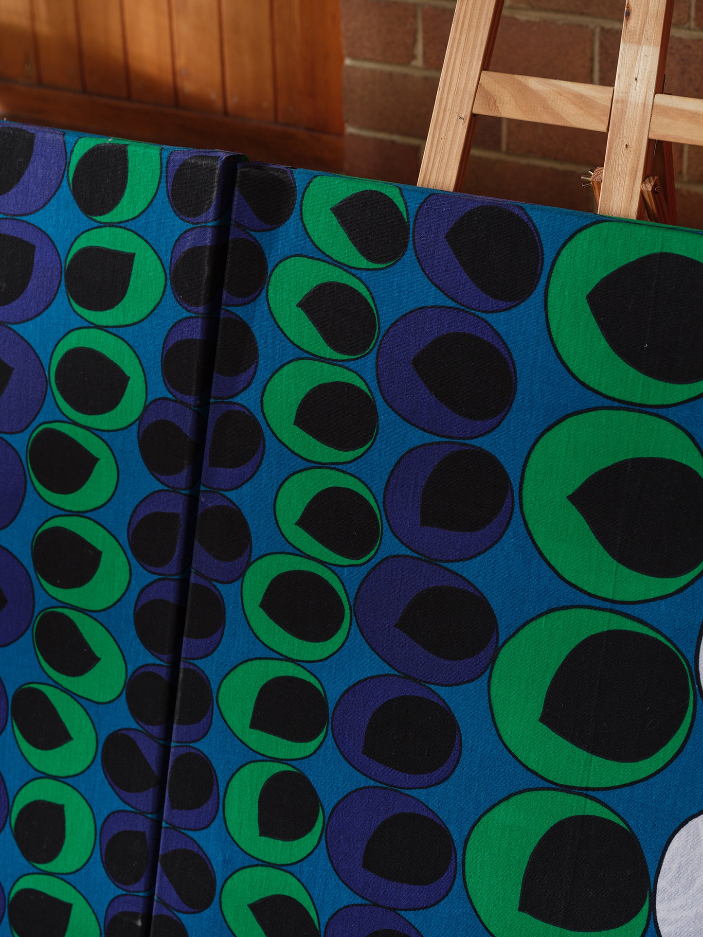 Peacock Rhythm Diptych, a set of two textile artworks with bold circular patterns in blue, green, black, and white, mounted on stretcher frames.