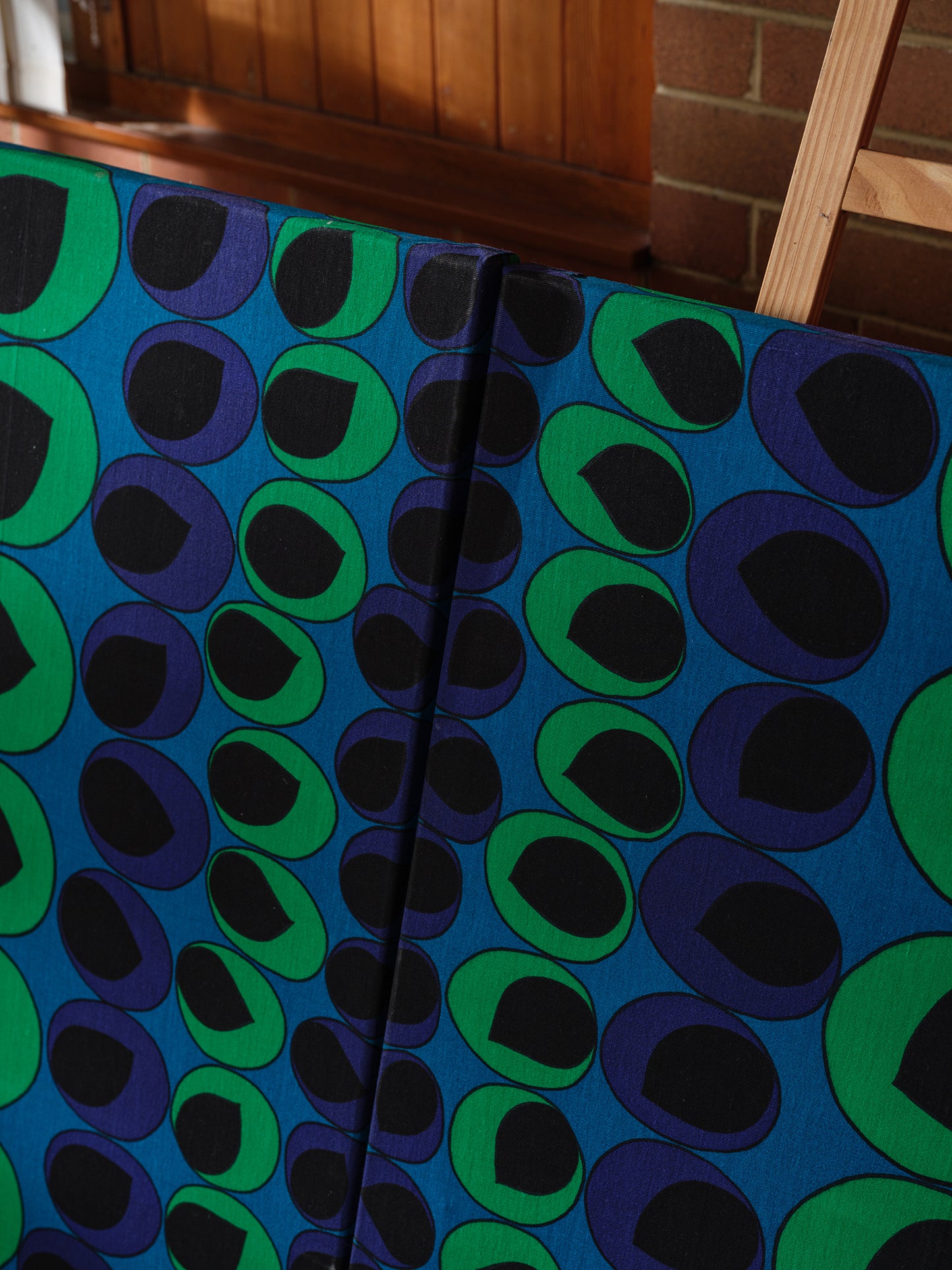 Peacock Rhythm Diptych, a set of two textile artworks with bold circular patterns in blue, green, black, and white, mounted on stretcher frames.