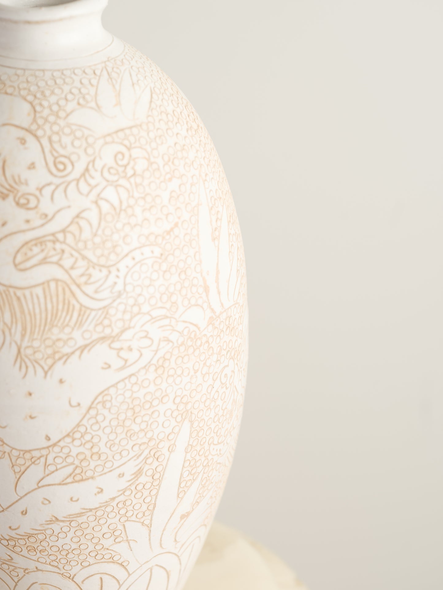 Sgraffito ceramic vase titled Qilin Whisper, featuring an ivory surface etched with a mythological qilin design in soft beige tones.