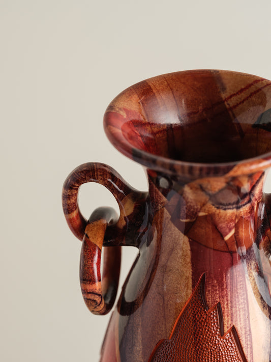 Decorative ceramic vase with red ochre glaze, featuring intricate carved motifs and twin ring handles.