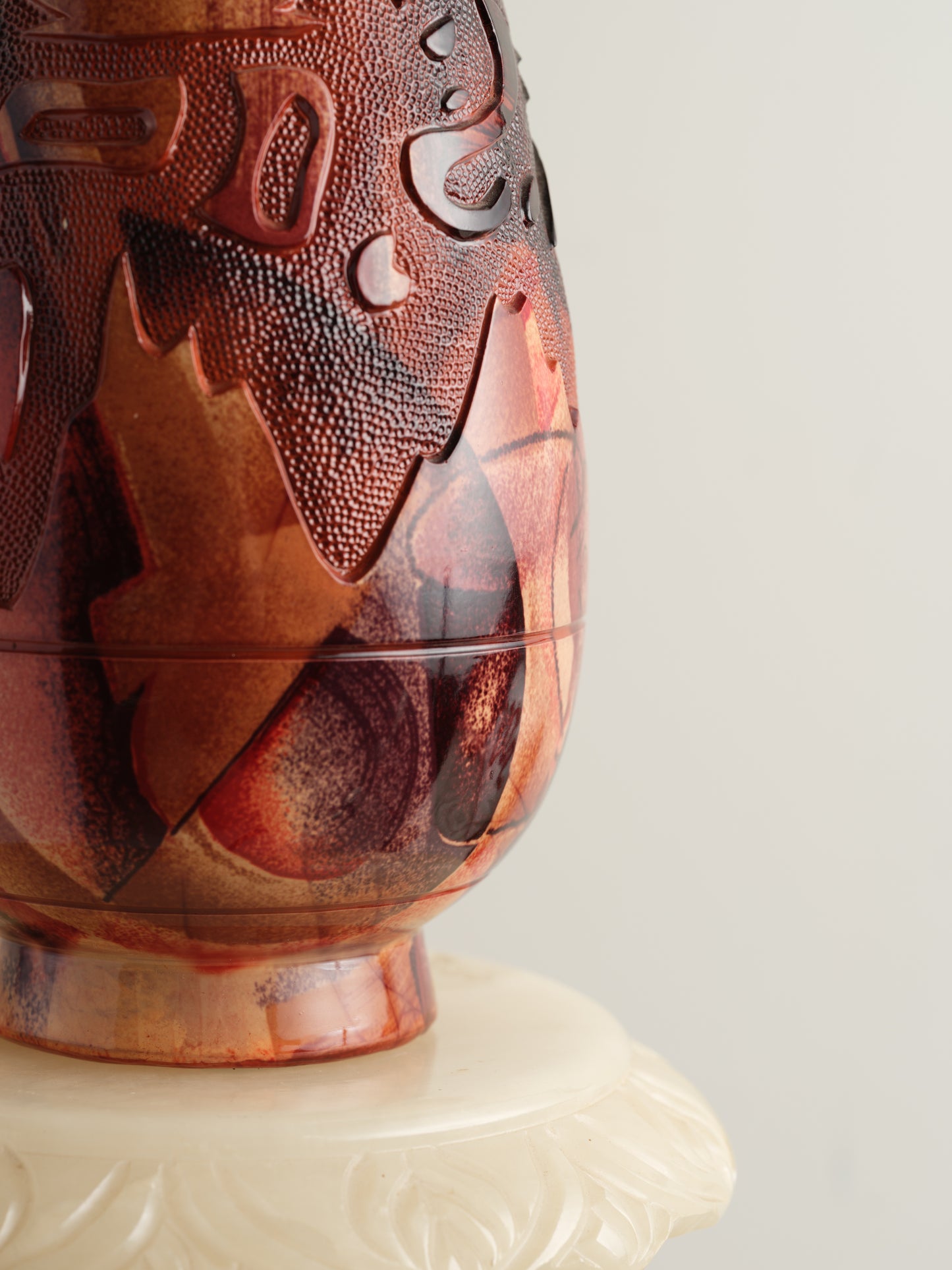 Decorative ceramic vase with red ochre glaze, featuring intricate carved motifs and twin ring handles.