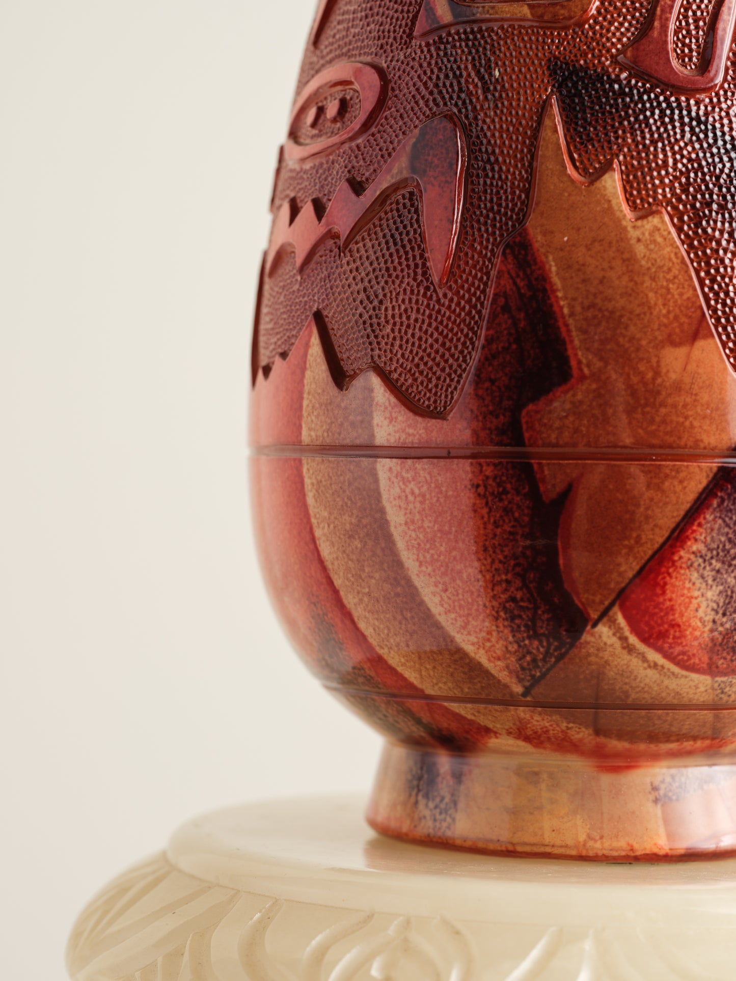 Decorative ceramic vase with red ochre glaze, featuring intricate carved motifs and twin ring handles.