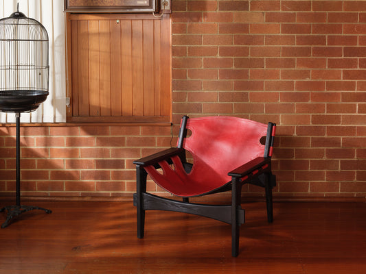 Replica Sergio Rodrigues Kilin lounge chair in red leather with black wooden frame with brick wall background