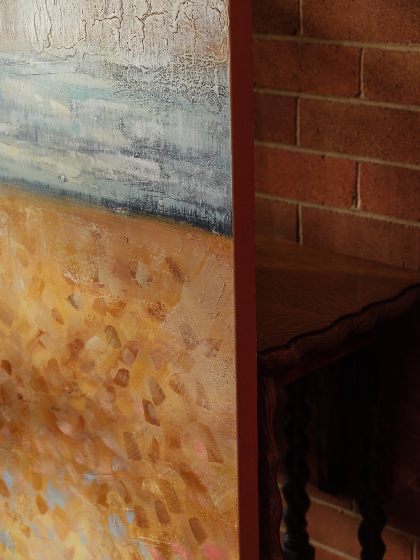 Abstract textured painting titled Shoreline Reverie, depicting layered sandy tones, soft blue horizon, and crackled surface evoking a weathered shoreline.