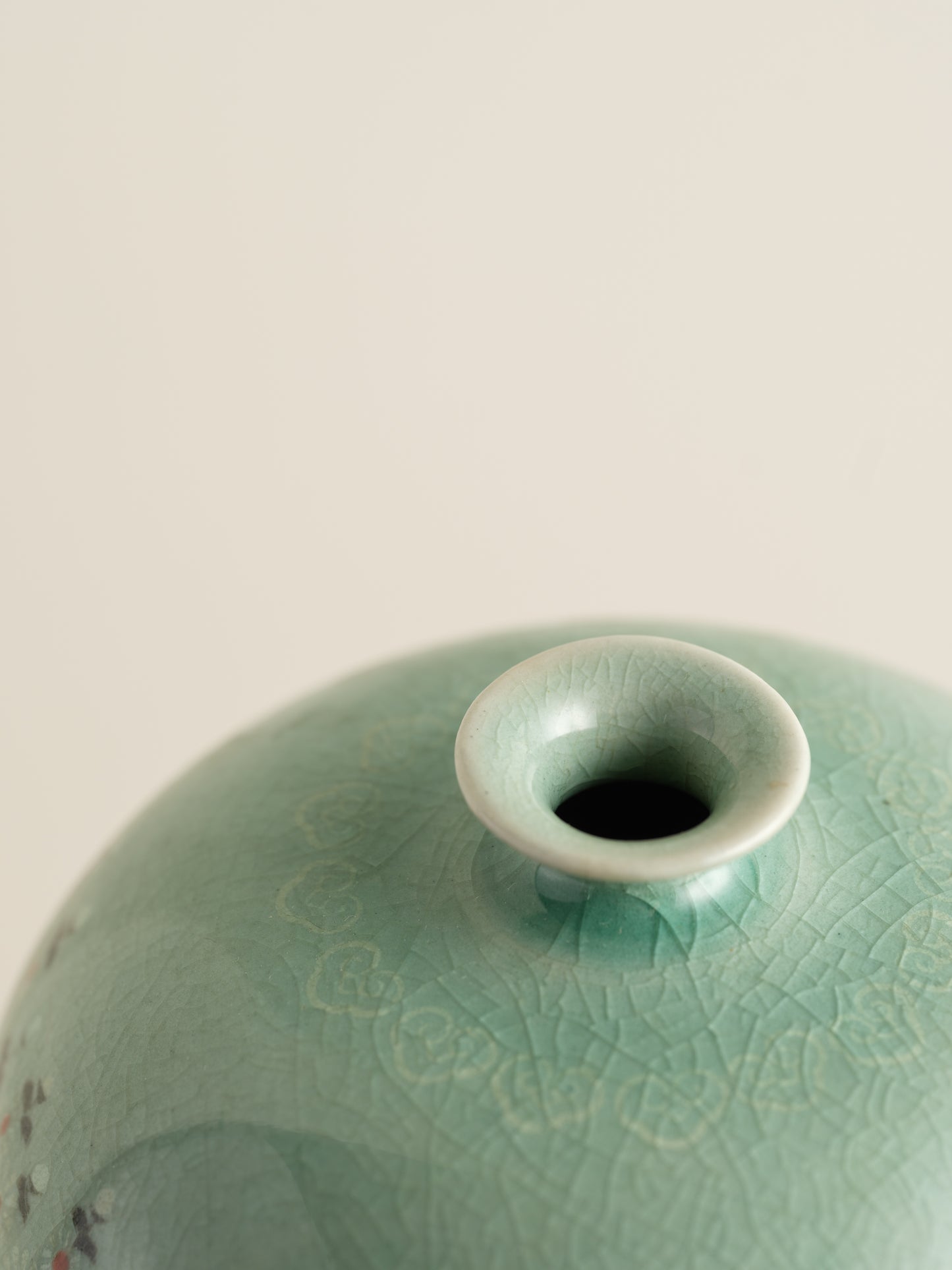 Small celadon bud vase in jade green glaze with hand-painted meadow flower motif around the shoulder.