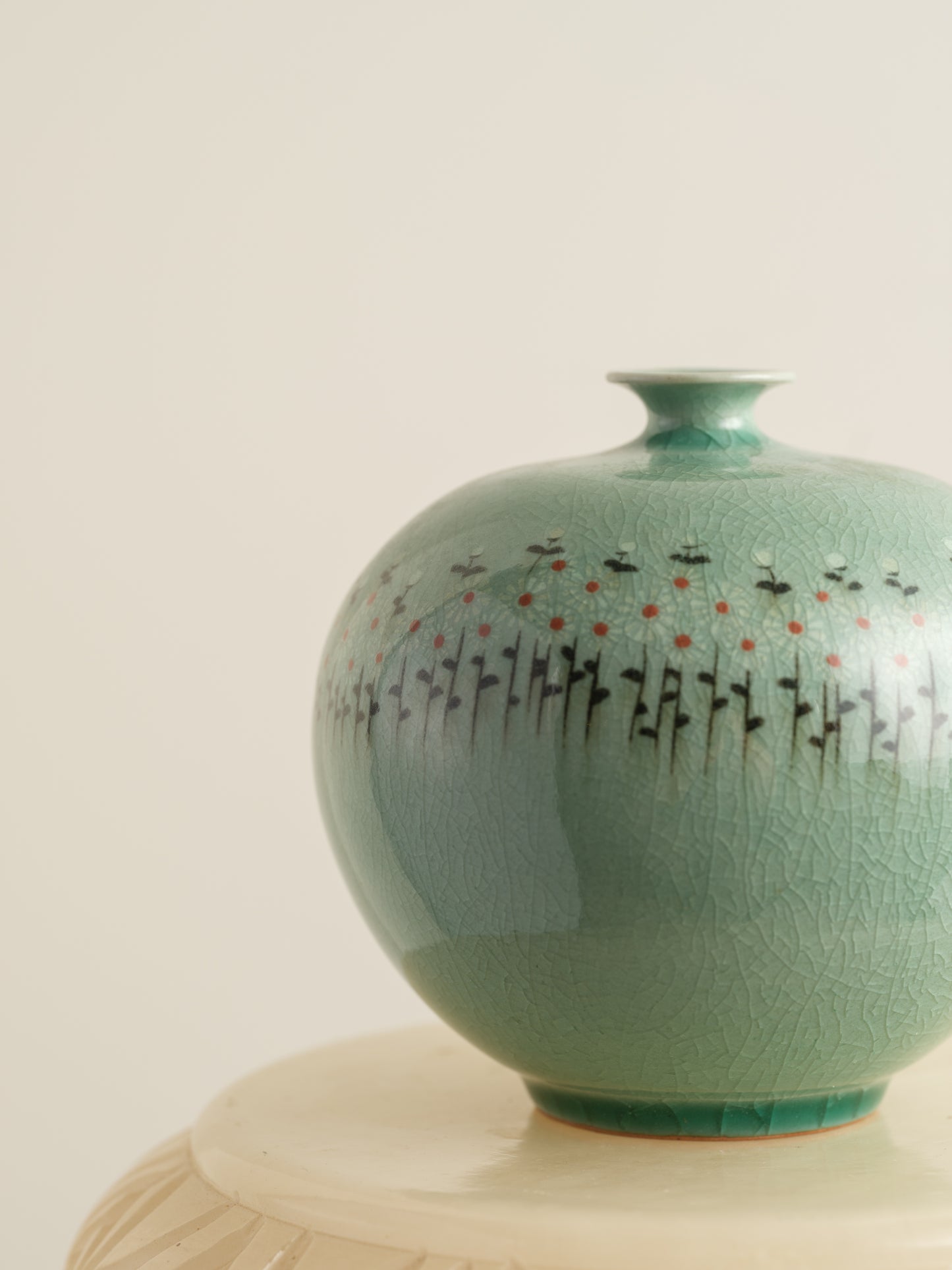 Small celadon bud vase in jade green glaze with hand-painted meadow flower motif around the shoulder.