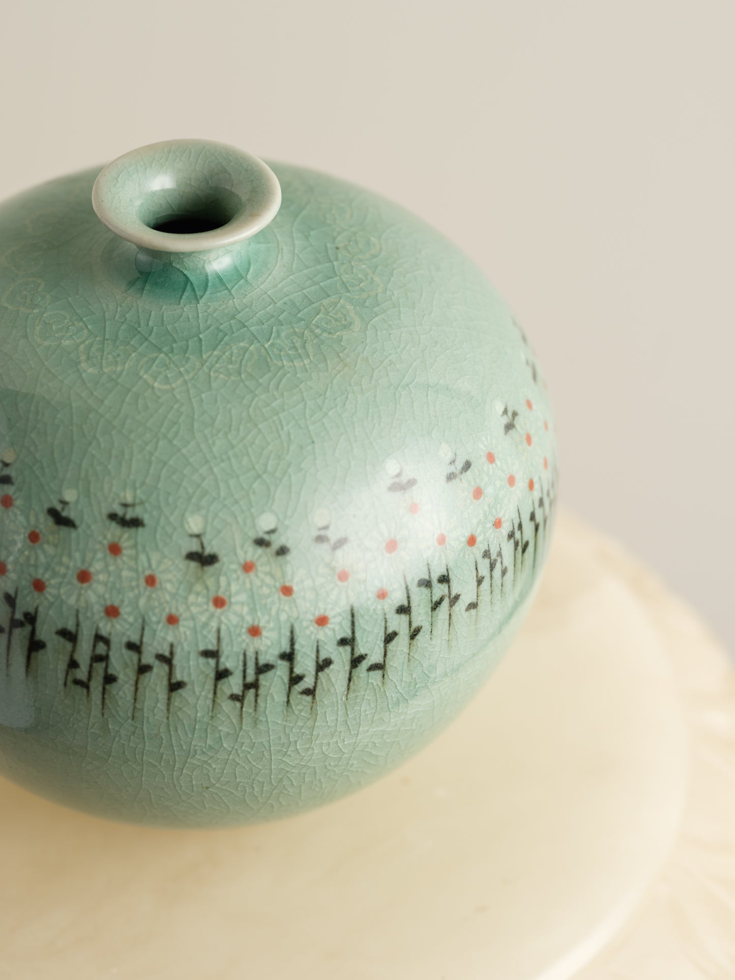 Small celadon bud vase in jade green glaze with hand-painted meadow flower motif around the shoulder.