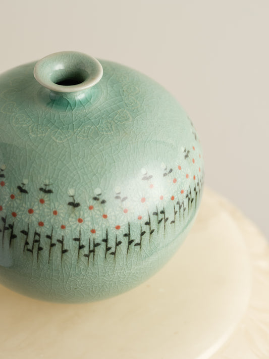 Small celadon bud vase in jade green glaze with hand-painted meadow flower motif around the shoulder.