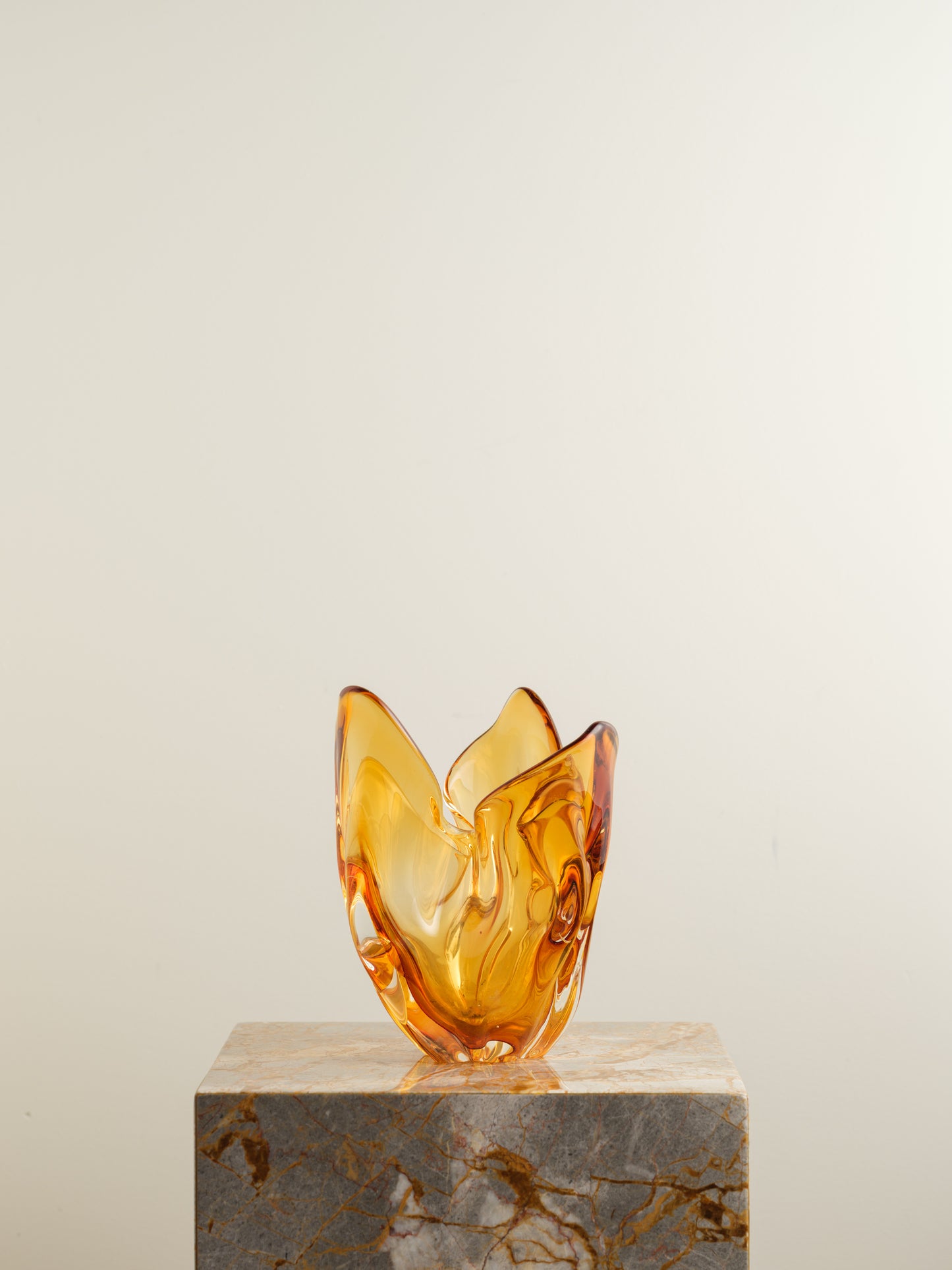 Amber-orange art glass vase with petal-like sculptural form and fluid edges.
