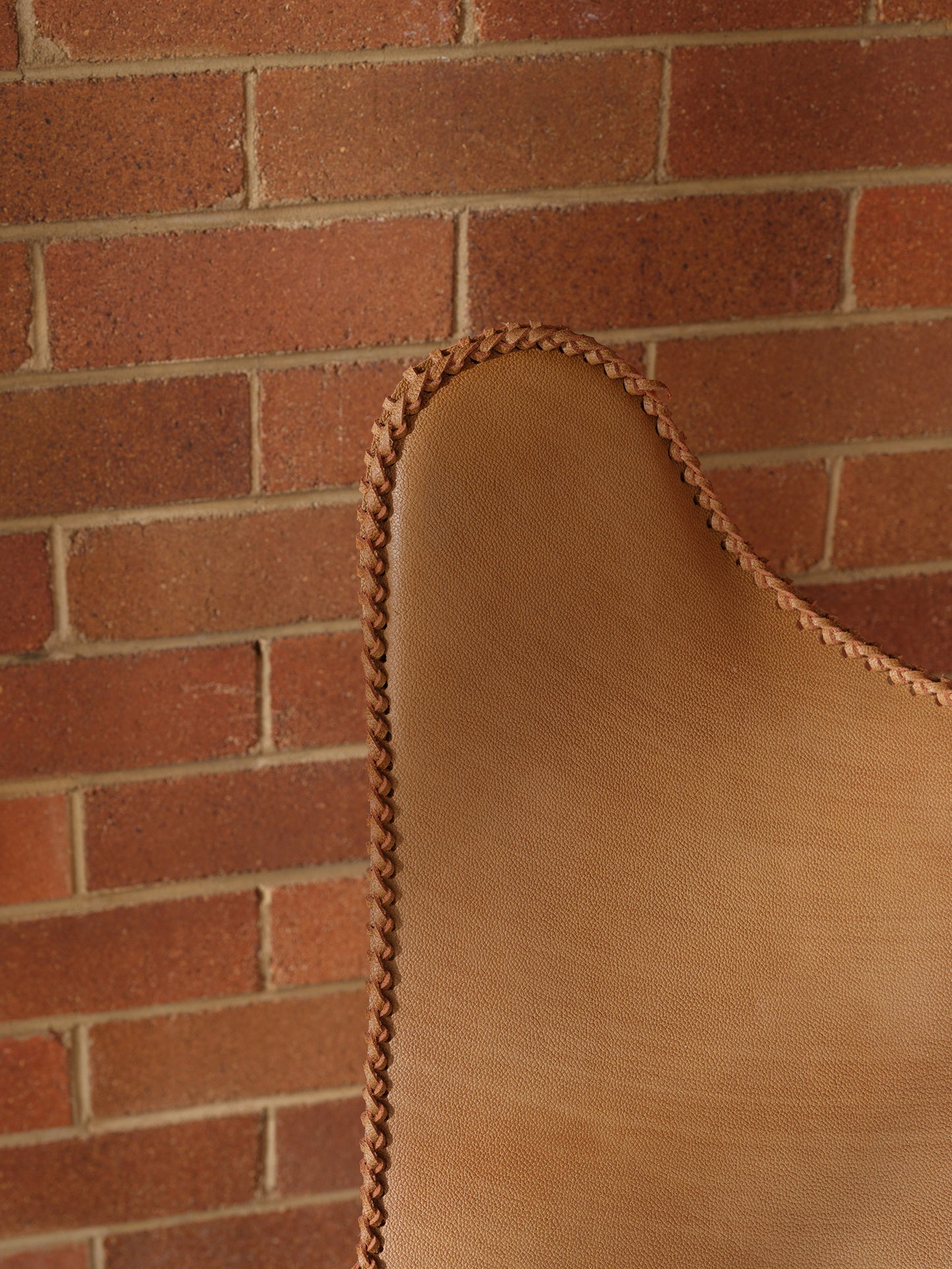 Tan suede butterfly lounge chair with stitched leather seat and metal frame, mid-century modern style