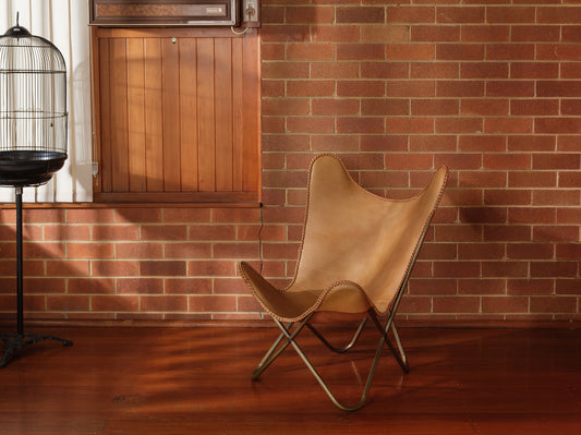 Tan suede butterfly lounge chair with stitched leather seat and metal frame, mid-century modern style