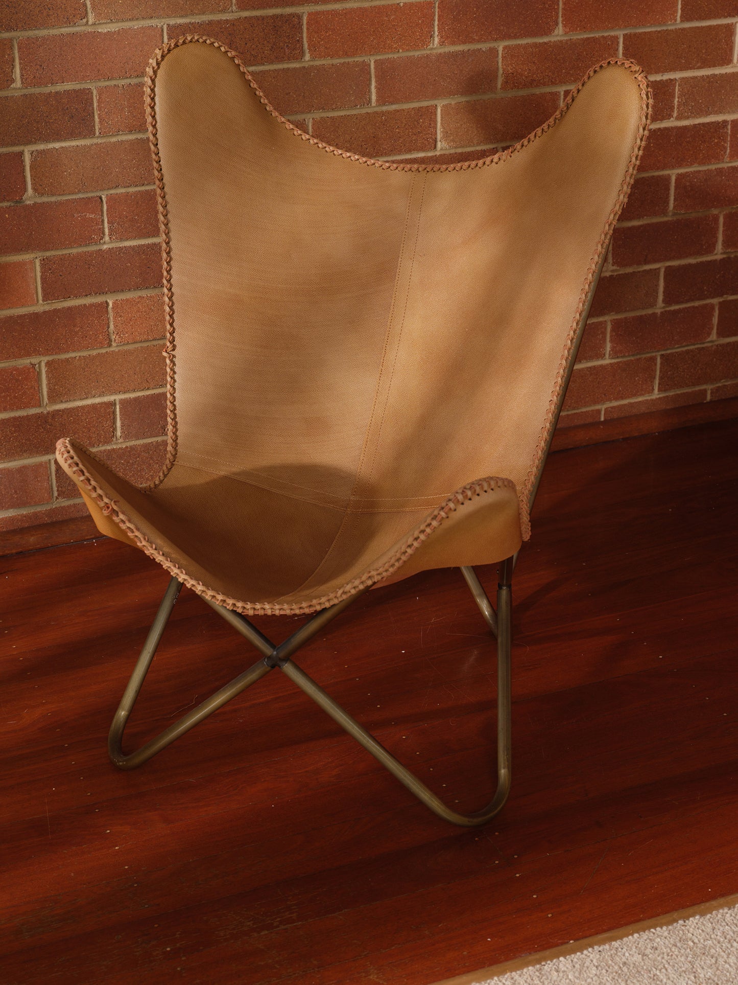 Tan suede butterfly lounge chair with stitched leather seat and metal frame, mid-century modern style