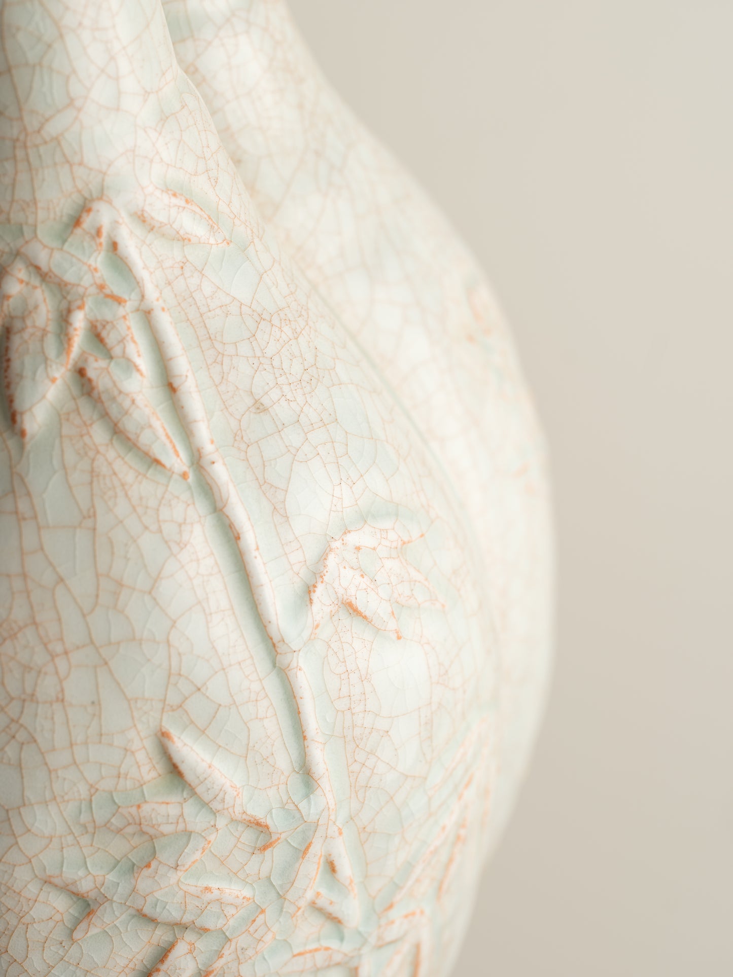 Celadon vase with three joined necks, embossed floral and bamboo motifs, and pale jade crackle glaze with russet tones.