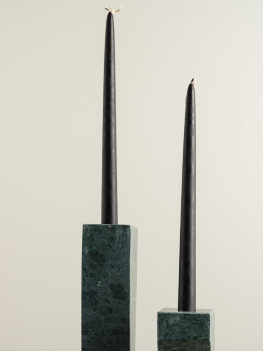 Pair of green marble candle holders with tall rectangular columns and black taper candles.