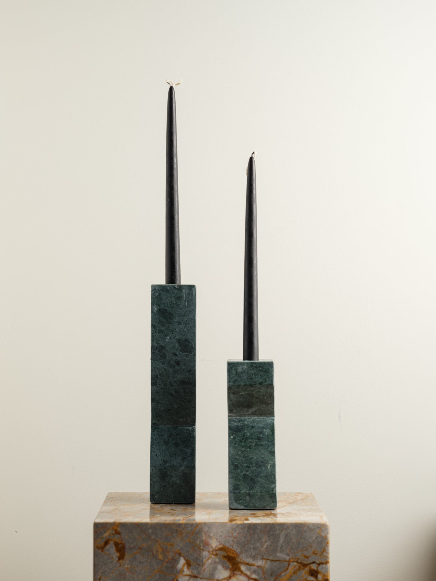 Pair of green marble candle holders with tall rectangular columns and black taper candles.