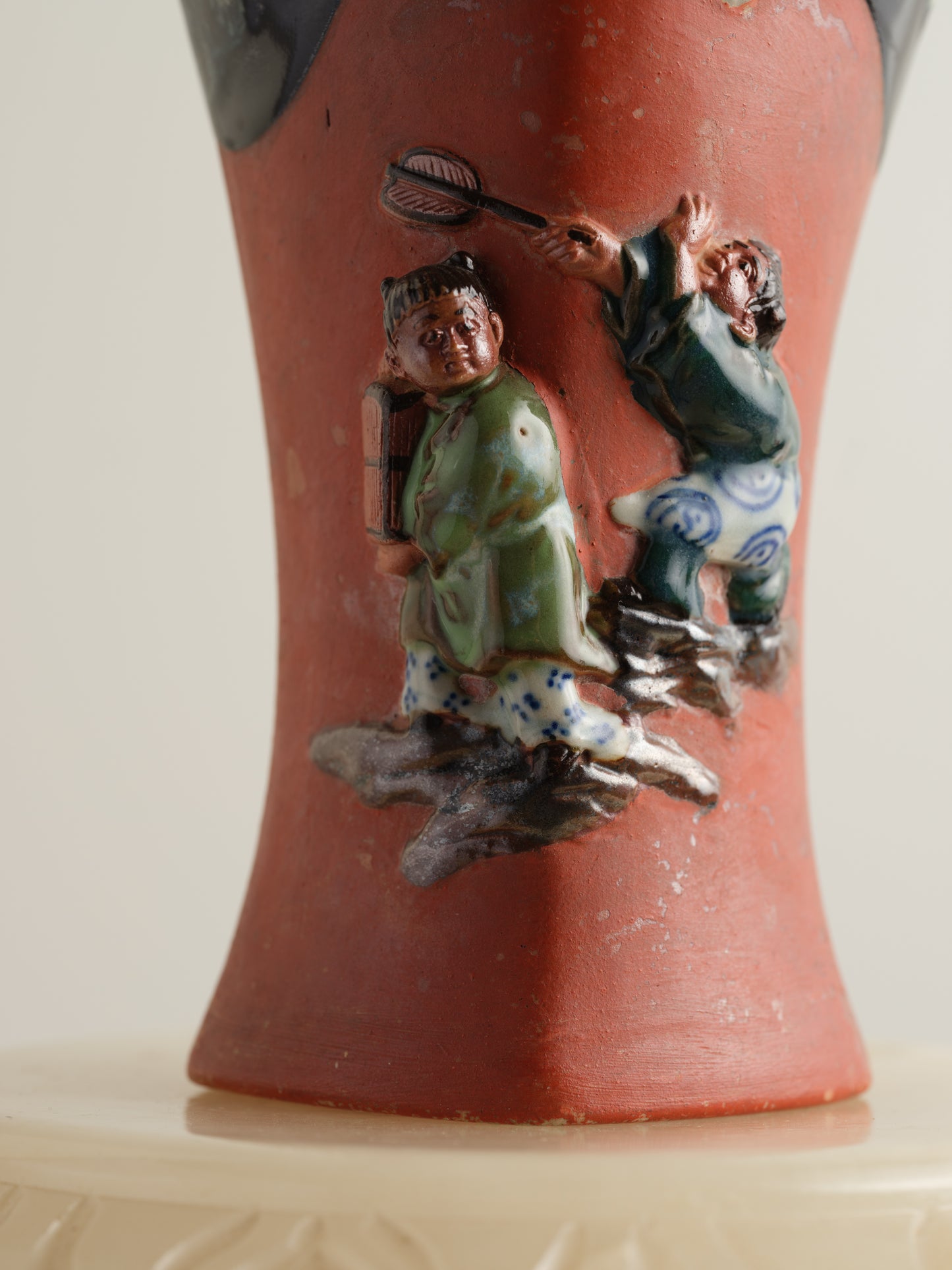 Vermilion Storyteller Relief Vase featuring hand-applied figurative relief on a tall form with dark glaze accents.