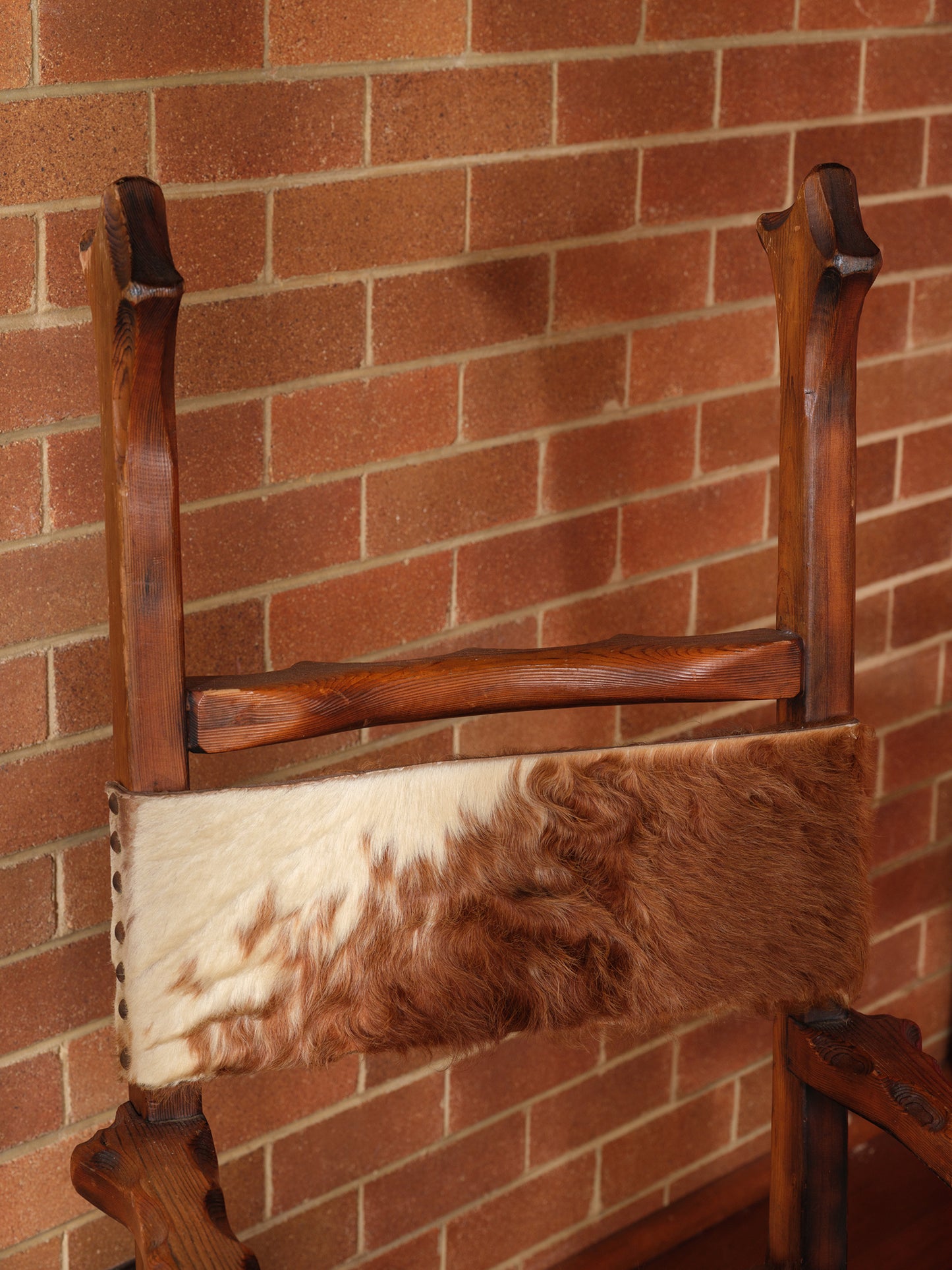 Wooden chair with a fur cushion against a brick wall