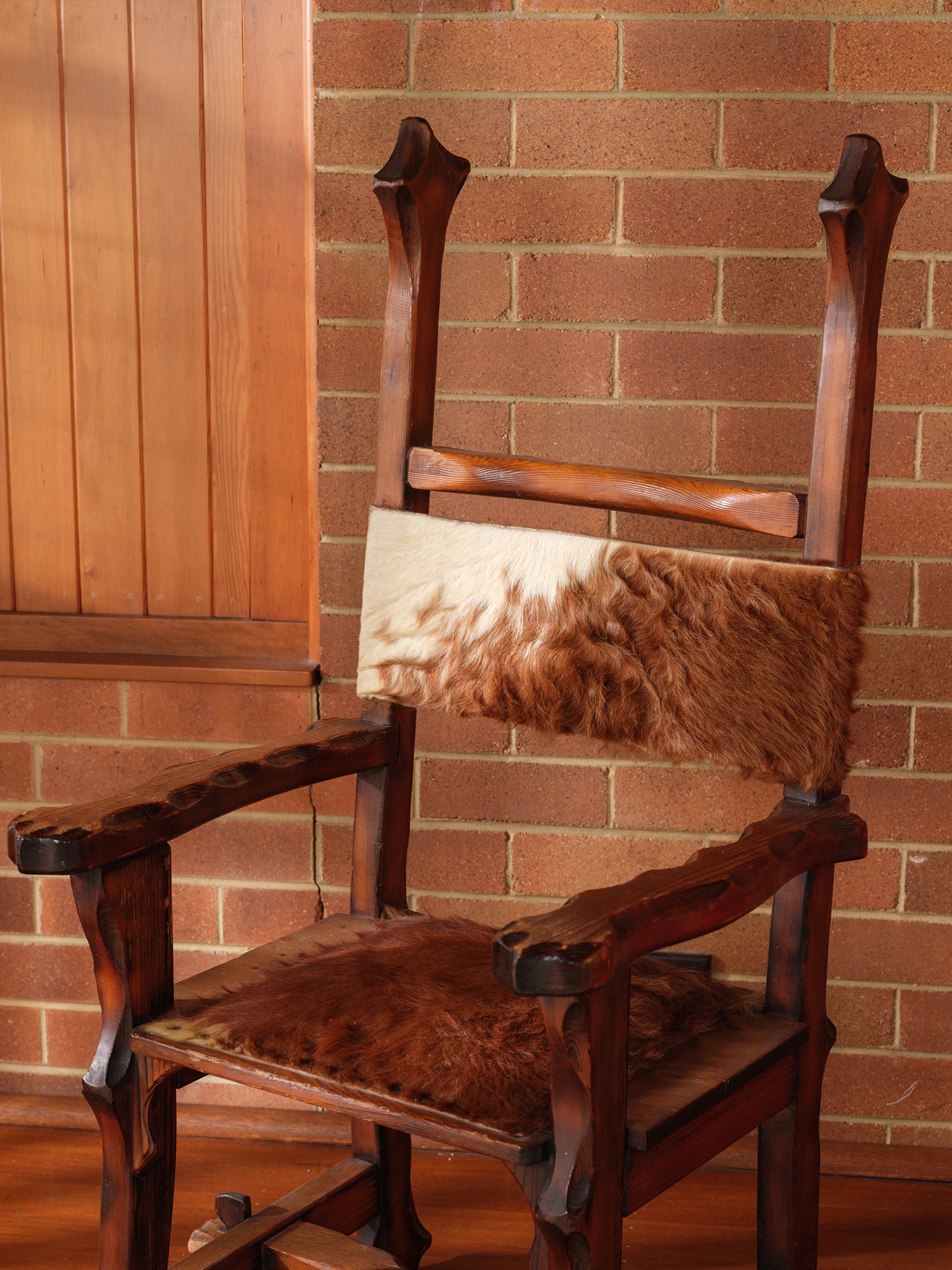 Wooden chair with a fur cushion against a brick wall